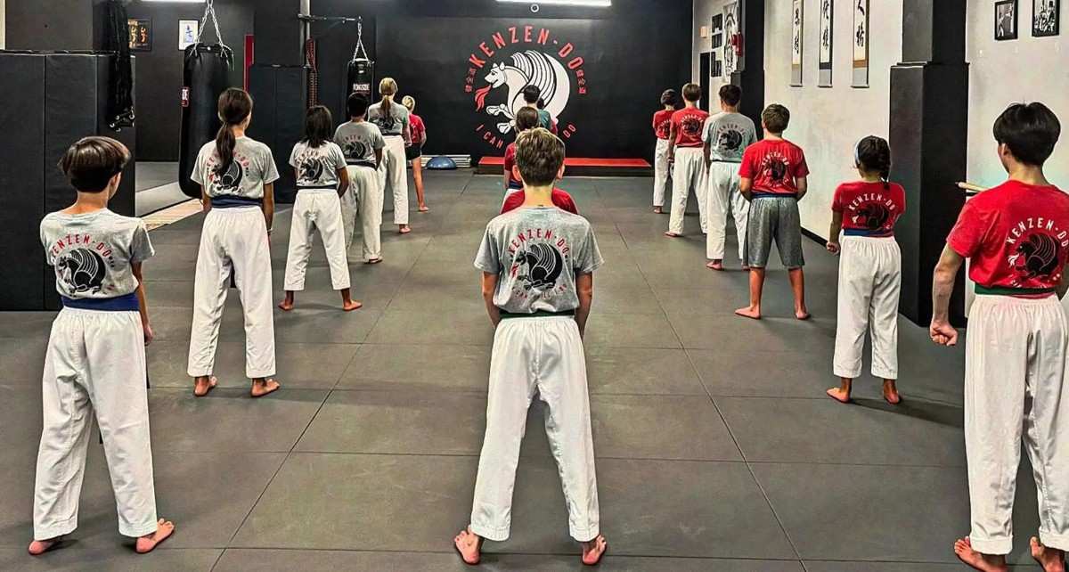 Children lined up in uniform practicing martial arts discipline and stance drills.