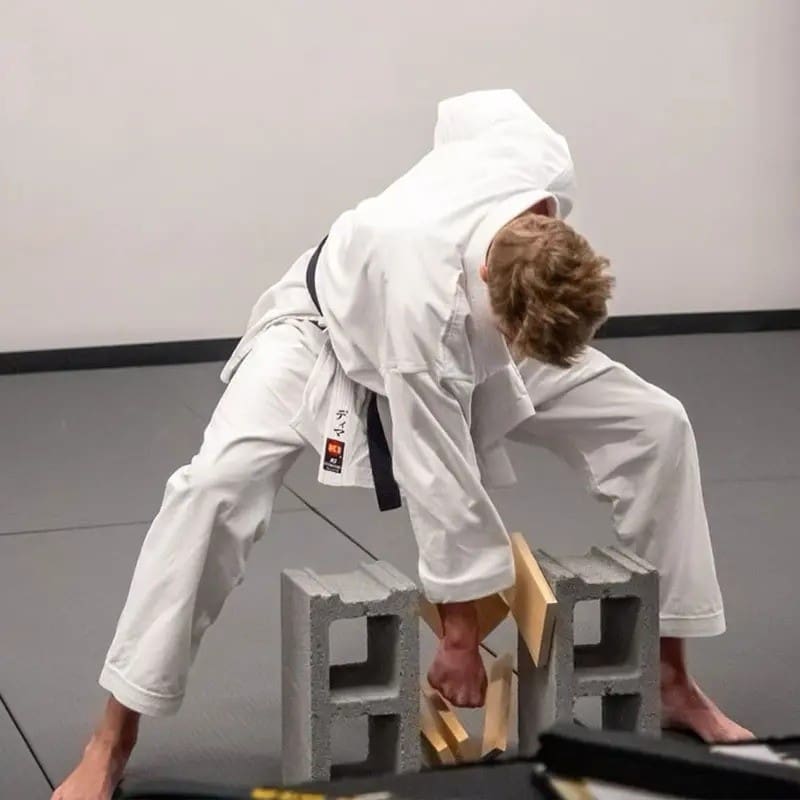 Martial arts student breaking wooden boards during a strength and focus demonstration.