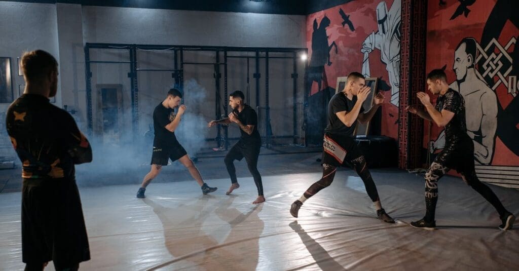 A group of men in athletic gear practicing striking and sparring drills during a martial arts training for adults class in a gym.