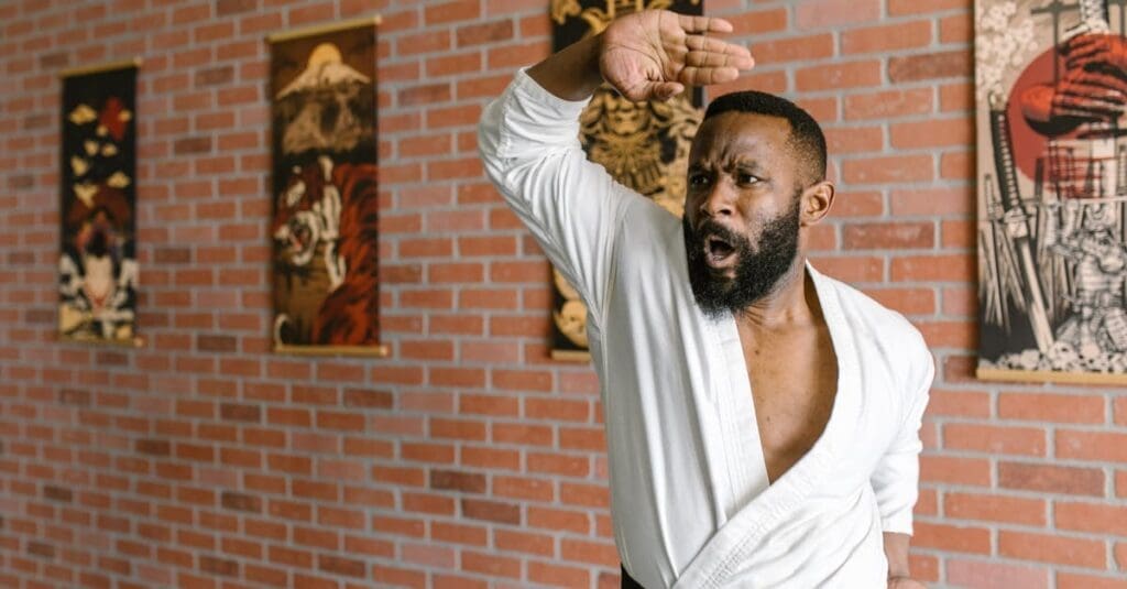 A man focusing on form and shouting while executing a defensive blocking stance during martial arts training for adults.