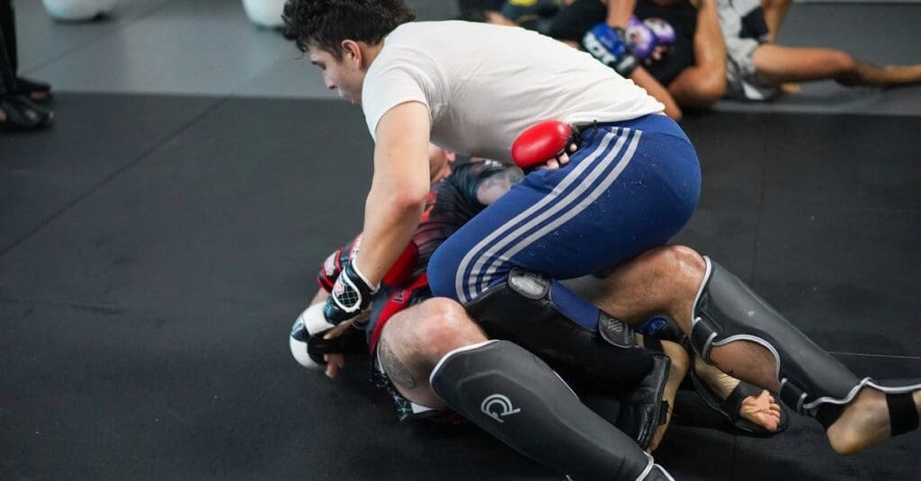 Two athletes practicing ground-and-pound and defensive guard transitions during an MMA-style martial arts training for adults class.