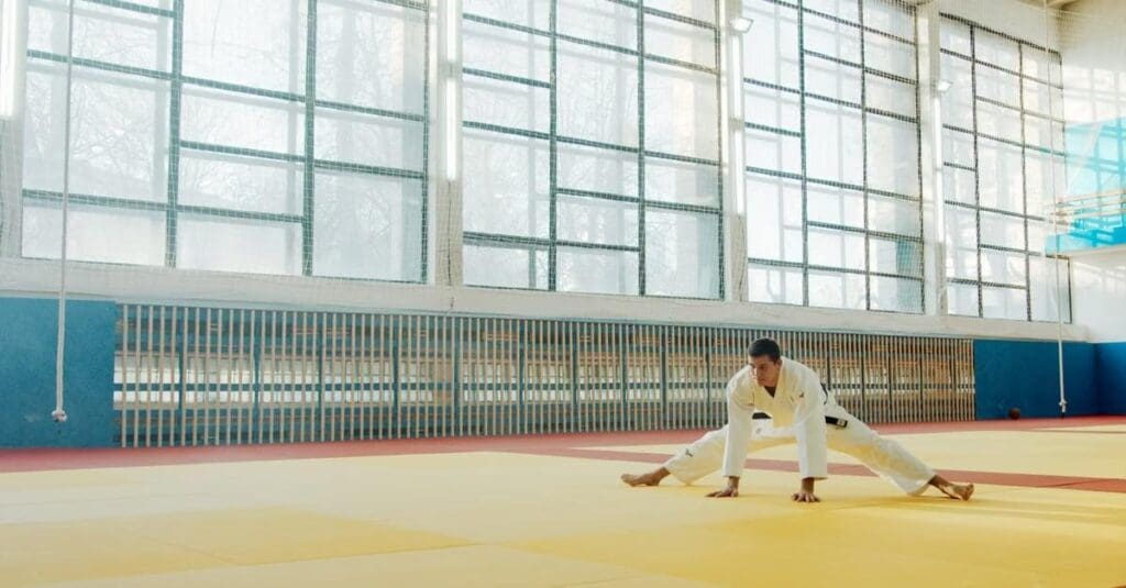 Adult martial artist performing a wide stretching exercise on training mats to improve mobility for adults taekwondo fundamentals.
