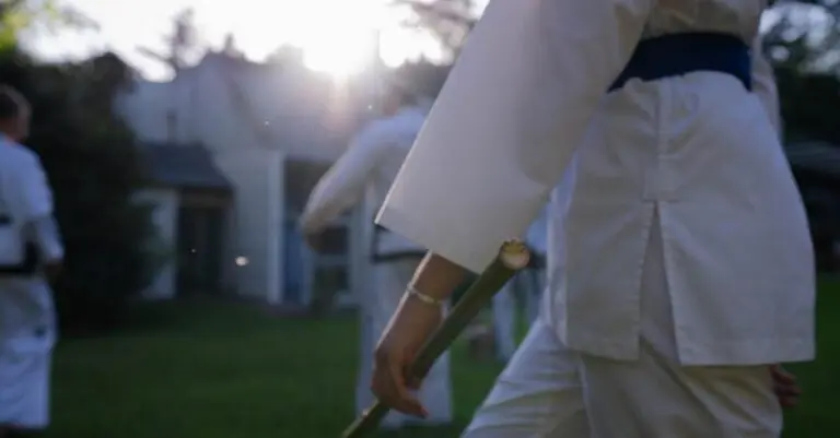 Adult martial artist carrying a training staff outdoors during structured practice connected to adults taekwondo fundamentals.