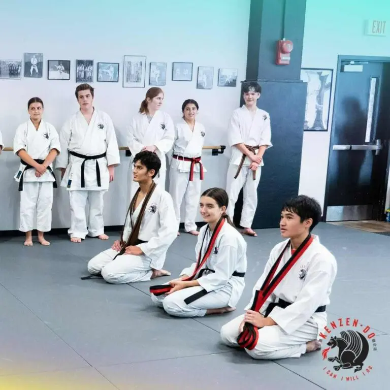 Taekwondo students kneeling and watching a belt ceremony or class recognition, showing what to expect in taekwondo class.