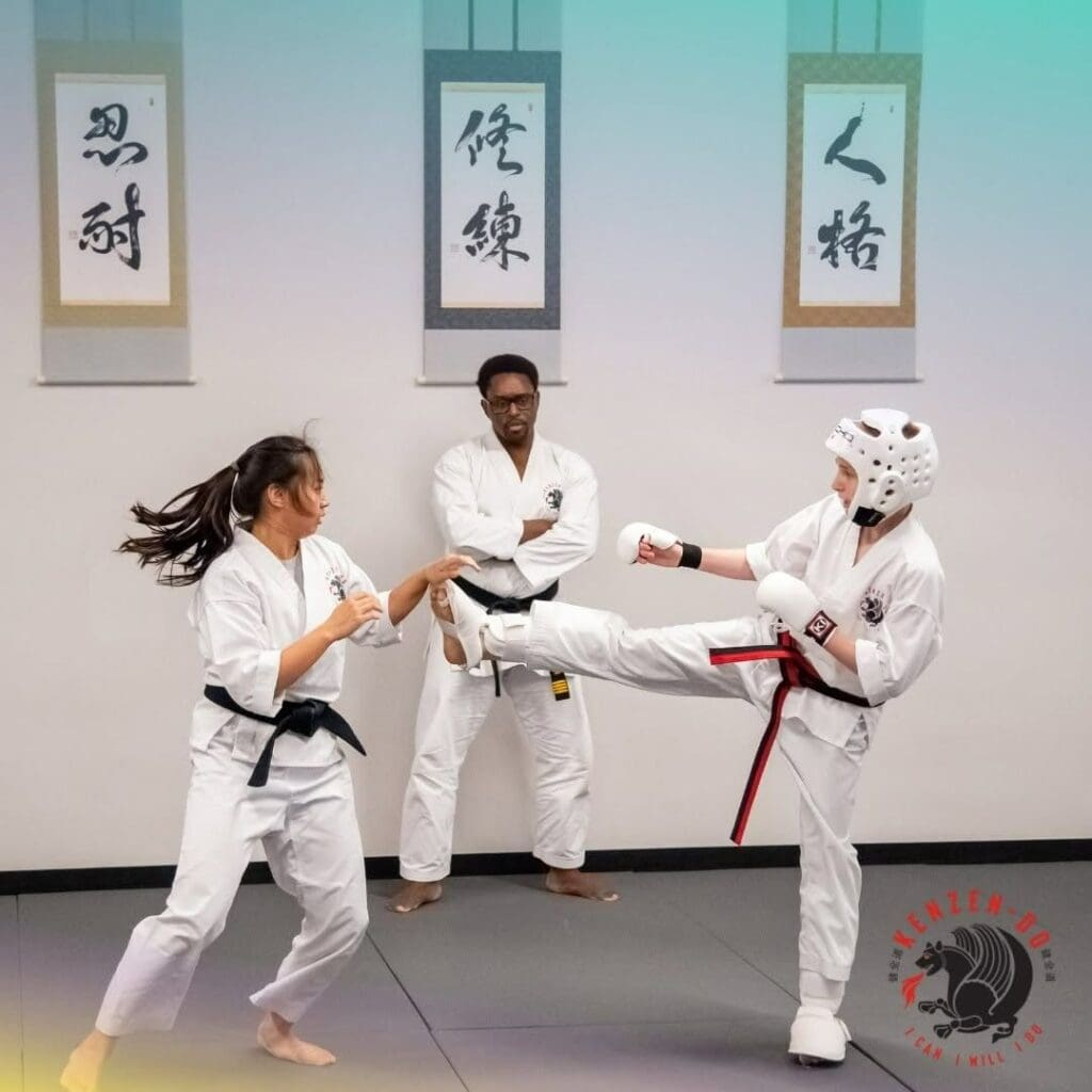 A young taekwondo student breaking a board with an instructor during a skills demonstration, showing what to expect in taekwondo class.